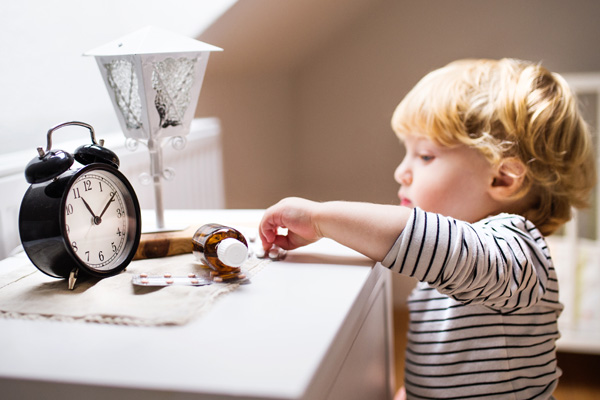 Child reaching for unsecured pills on a nightstand in a home environment