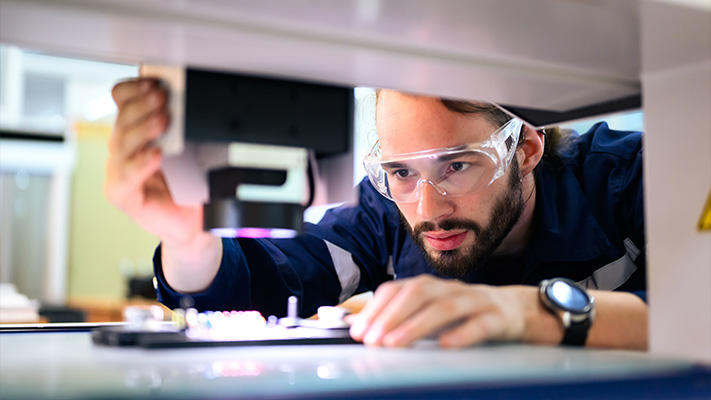 Engineer inspecting circuit board during electronics product development using microscope