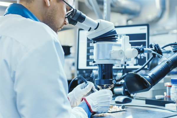 Electronics technician repairing a damaged PCB on a lab bench, representing field failure analysis.