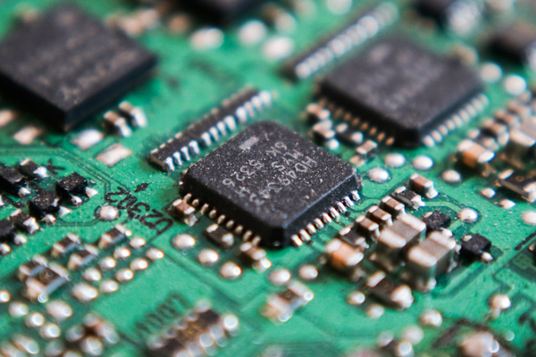 Extreme close-up of a contaminated circuit board with visible dust, debris, and possible conductive residue