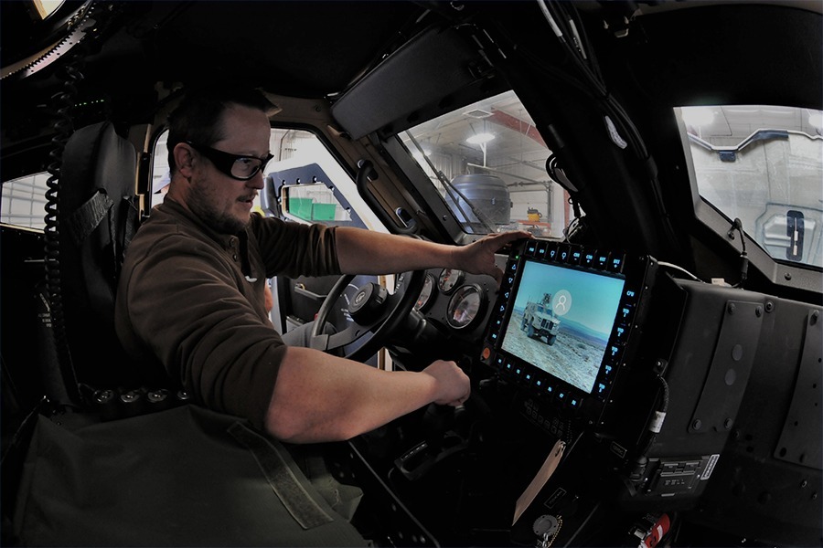 Technician working with electronic systems inside a tactical vehicle